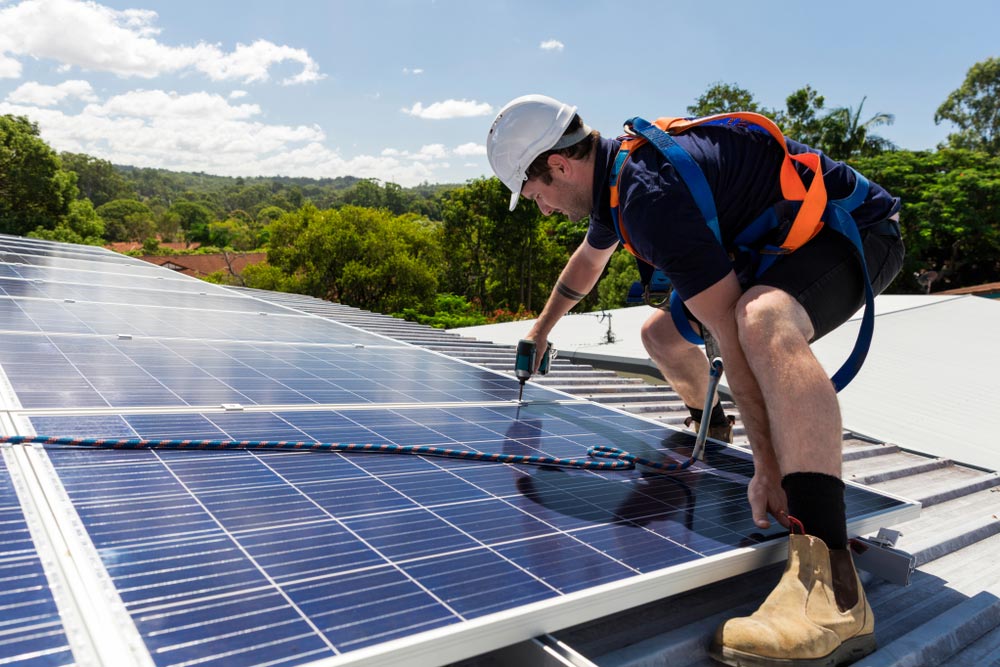 Man Installing Solar Panel On Roof